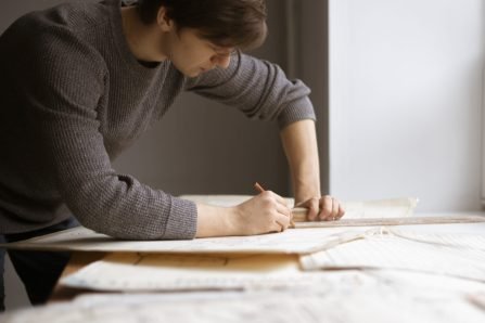 caucasian young architect doing drawings at the workplace, making the sketch or draft of new building