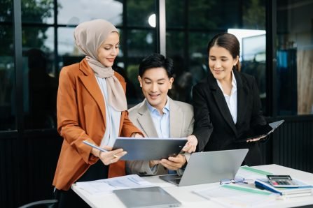 Happy Asian businesspeople while collaborating on a new project.  using a laptop and tablet are brainstorming planning discussing while sitting in office